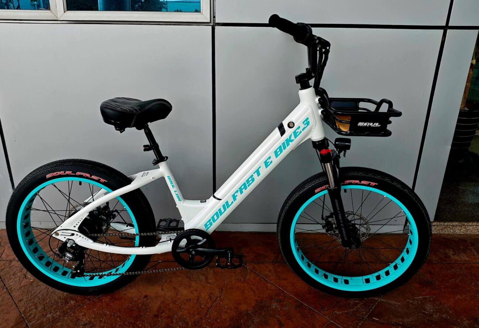 White electric bike with turquoise wheels.