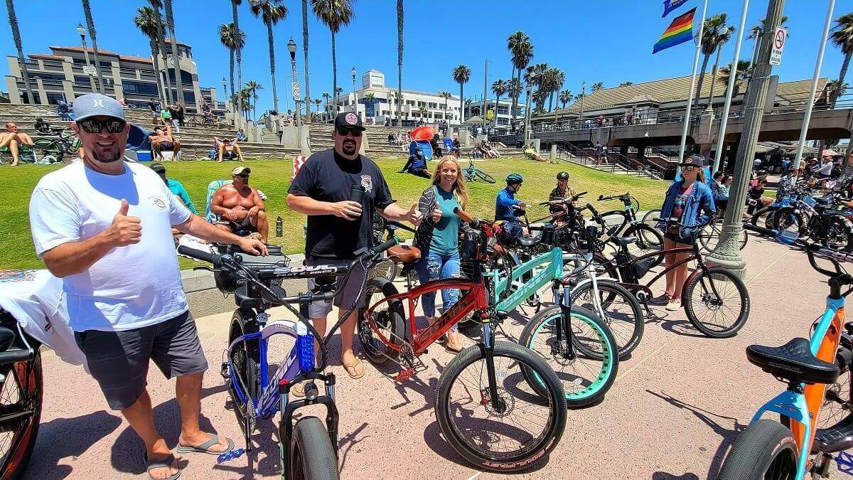 Group of people with bicycles near beach.