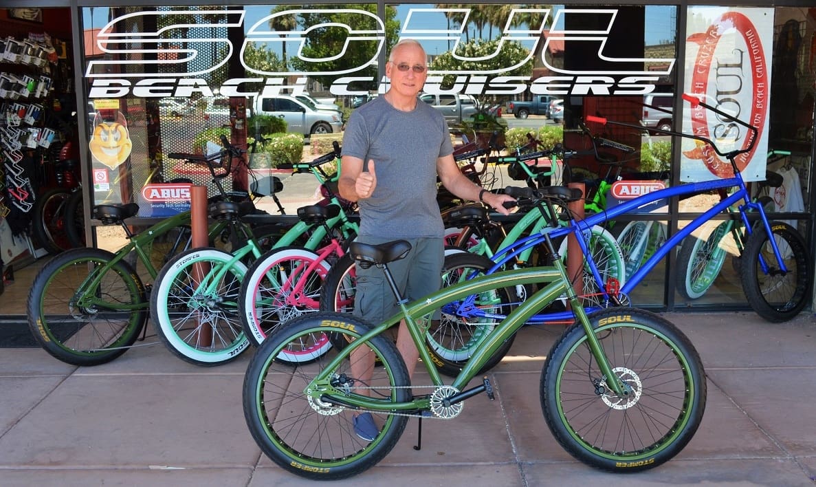 Man standing with colorful beach cruiser bicycles.