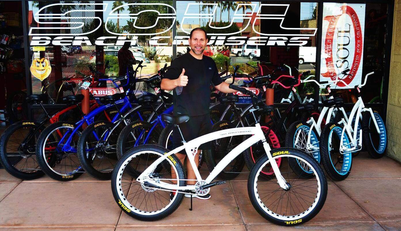 Man smiling with bicycles at shop entrance.