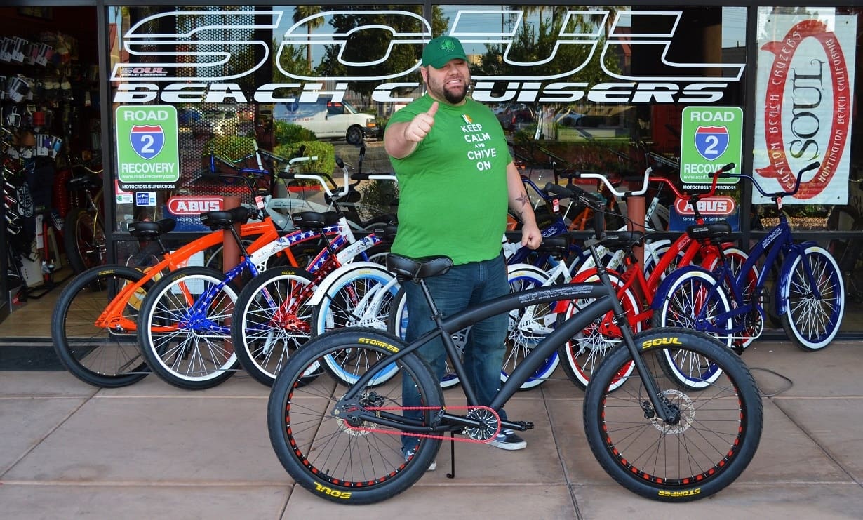 Man posing with bicycles outside a shop.