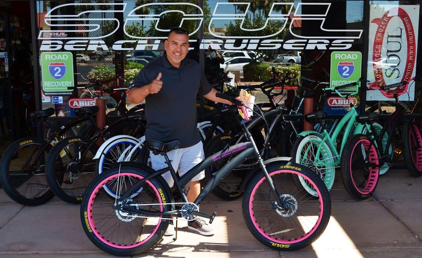 Man with bicycle in front of store.
