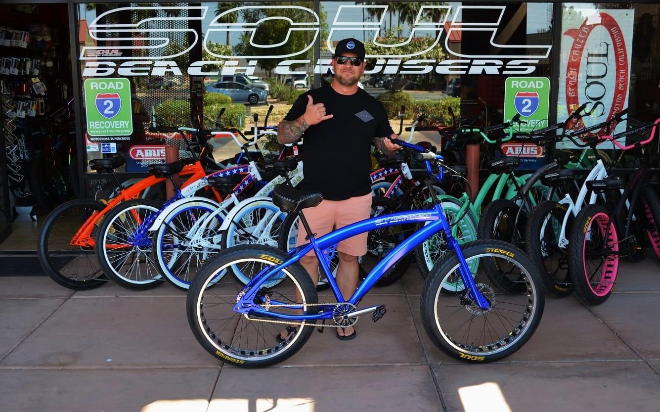 Man standing with a blue beach cruiser.