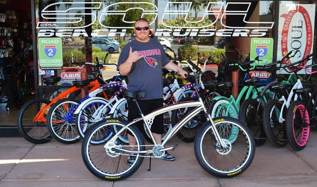 Man holding a bicycle outside bike shop.