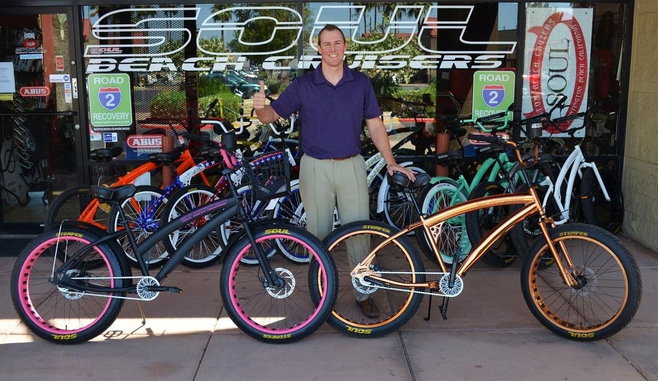 Man standing with multiple colorful bicycles.
