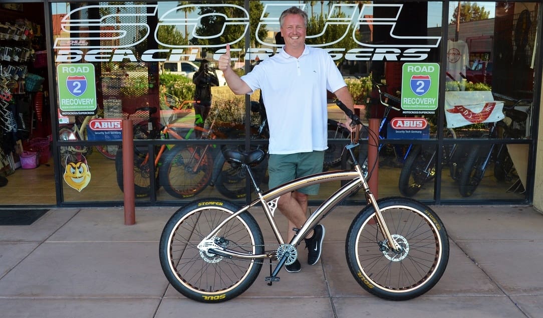 Man standing with a beach cruiser bicycle.
