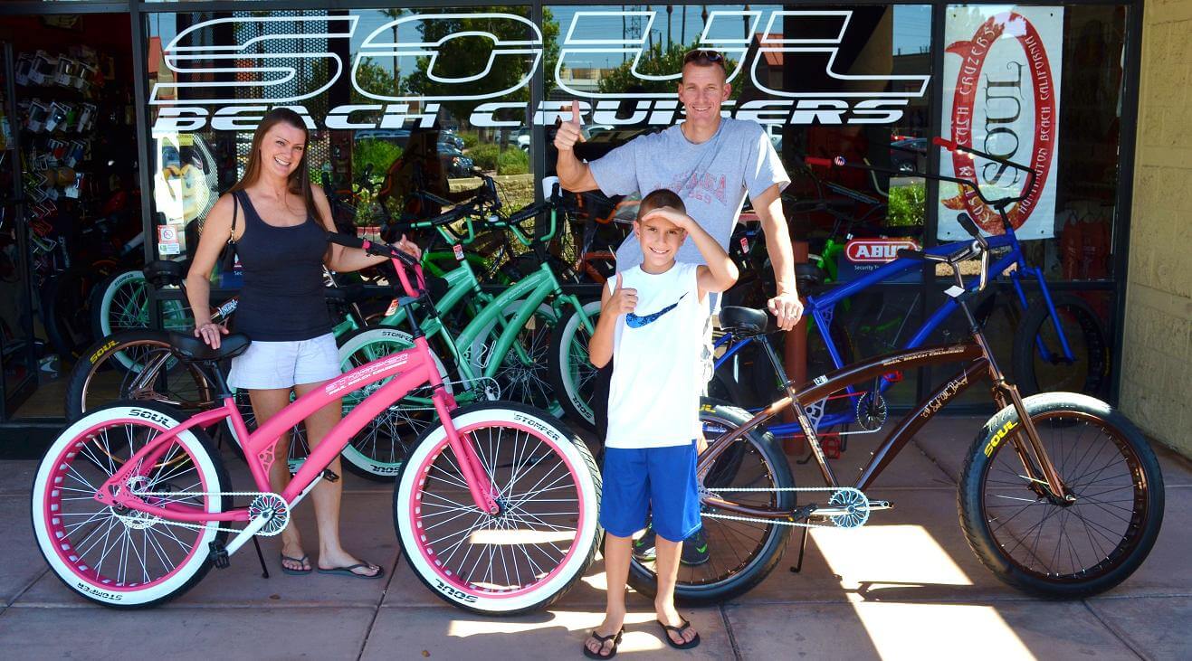 Family posing with colorful beach cruiser bikes.