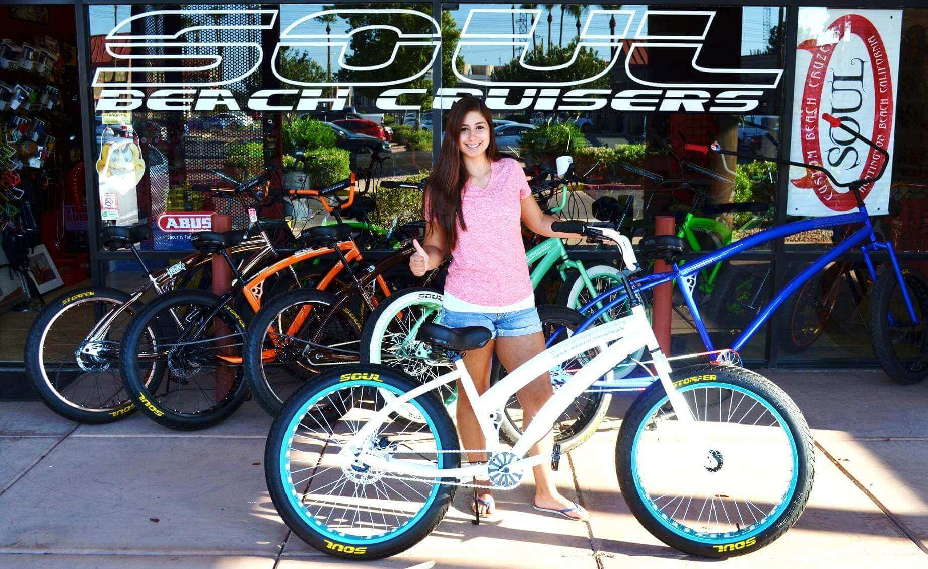 Woman with bicycle outside bike shop.