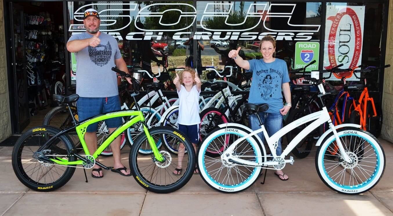 Family posing with cruiser bicycles outside shop.