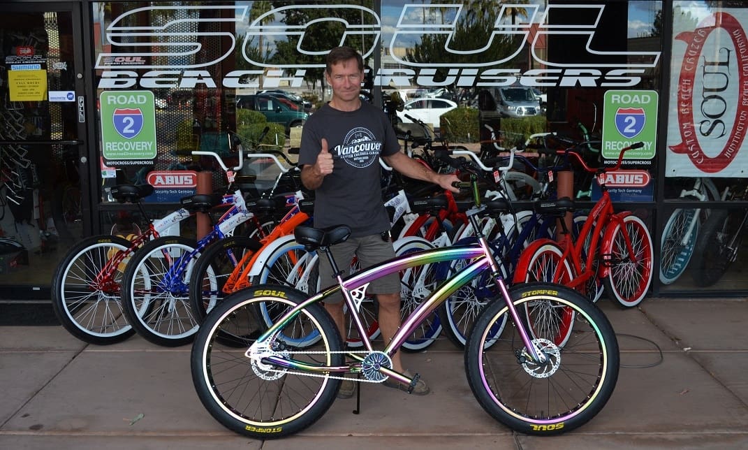 Man standing with colorful bicycles in store.