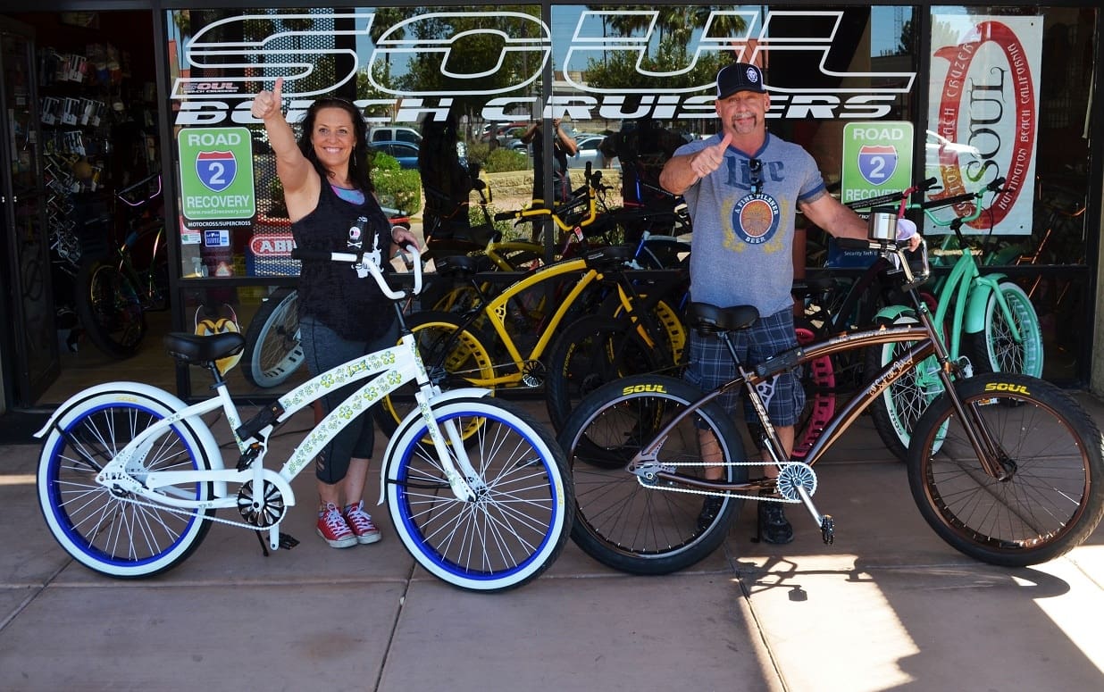 Two people with beach cruiser bicycles.