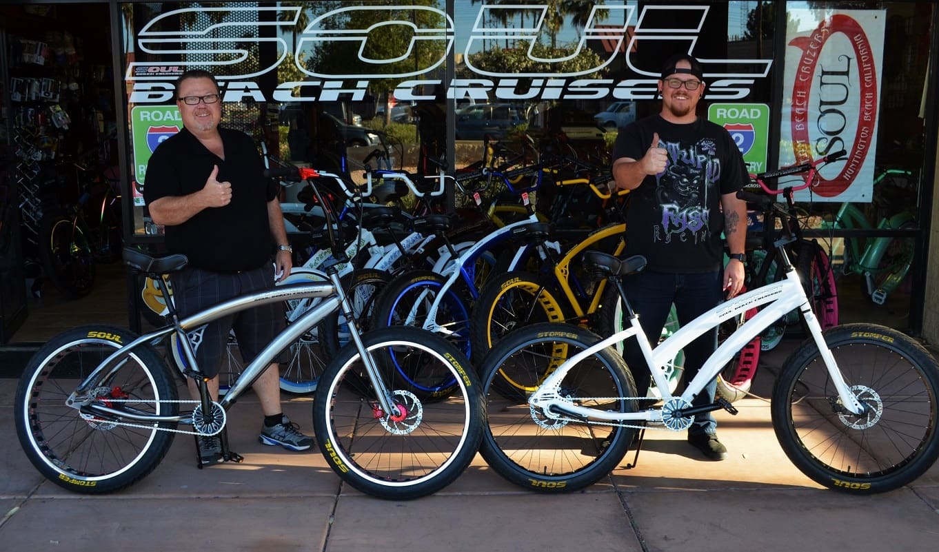 Two men with bicycles, giving thumbs up.