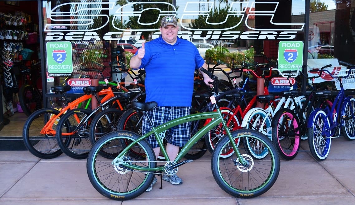 Man posing with bicycles outside a shop.