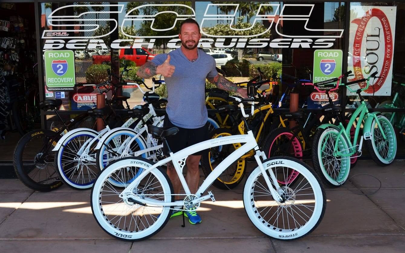 Man with bicycle in front of bike shop.