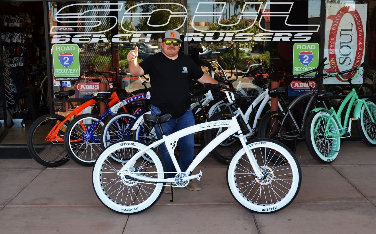 Man posing with a white beach cruiser.