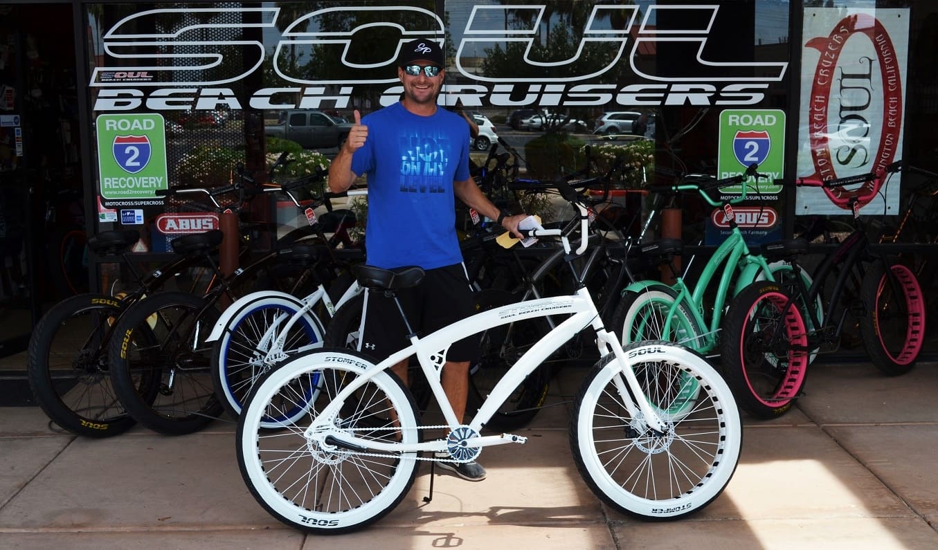 Man with bicycle in front of bike shop.