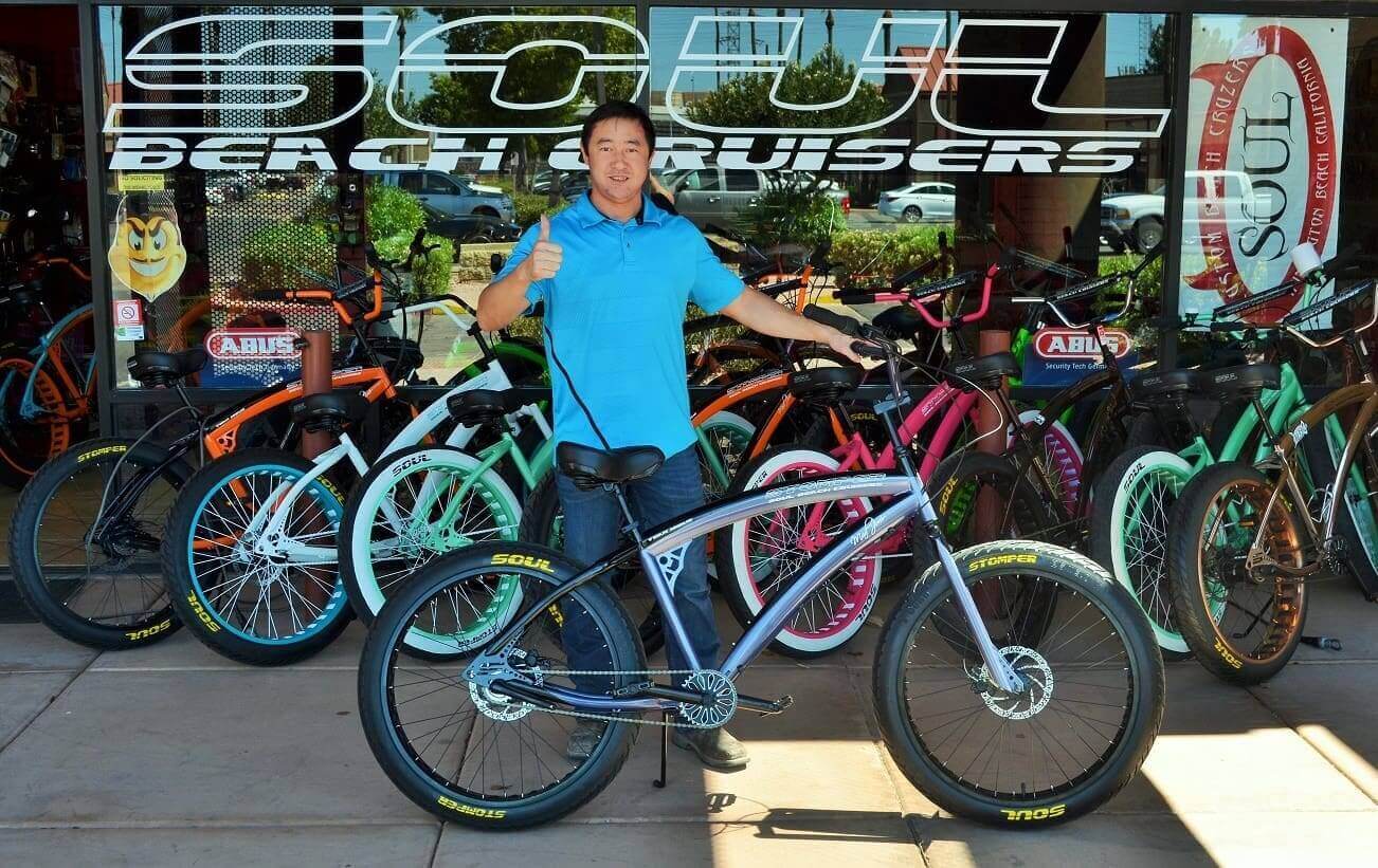 Man with bicycle outside bike shop.