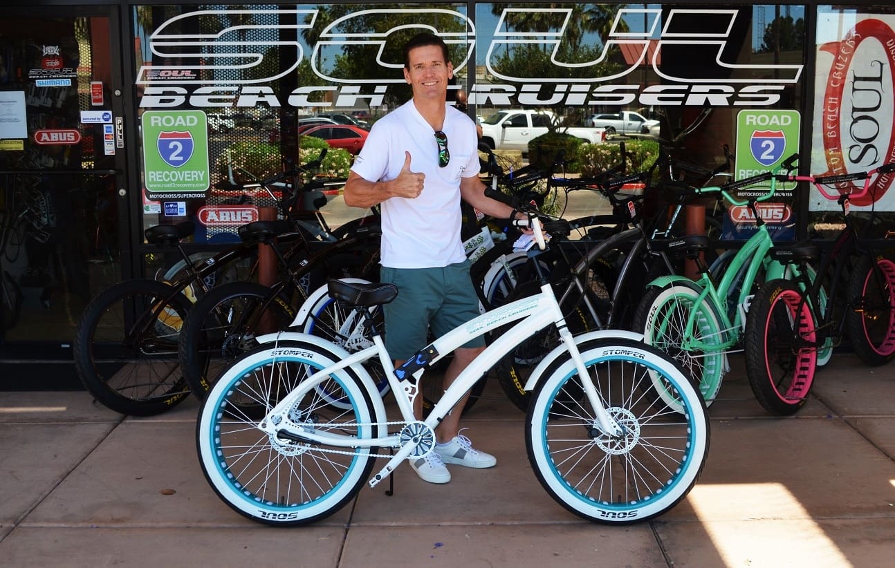 Person posing with a white beach cruiser.