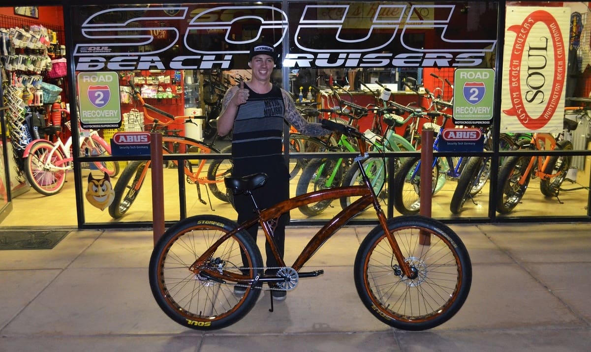 Person smiling with bicycle outside bike shop.
