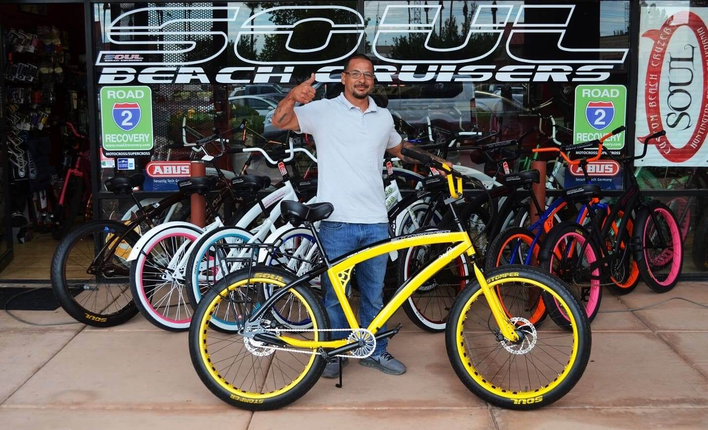 Man posing with yellow beach cruiser bicycle.