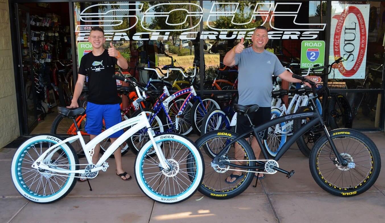 Two men with bicycles outside a store.