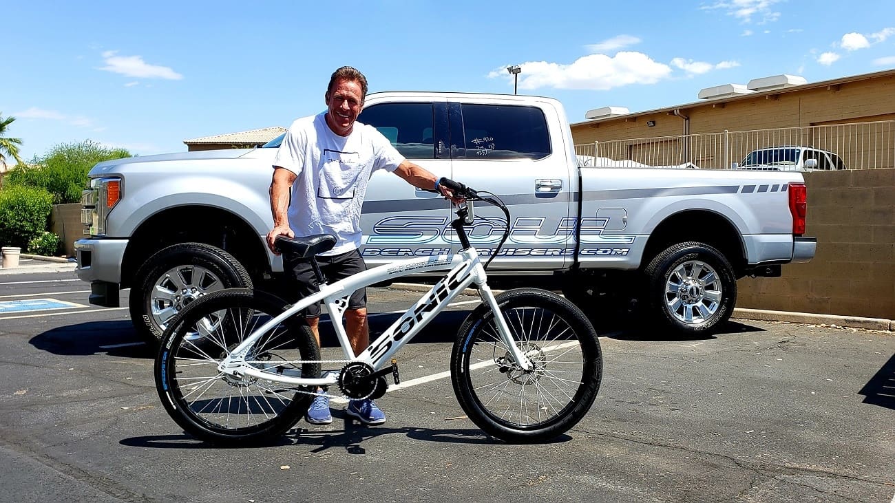 Man with bicycle in front of truck.