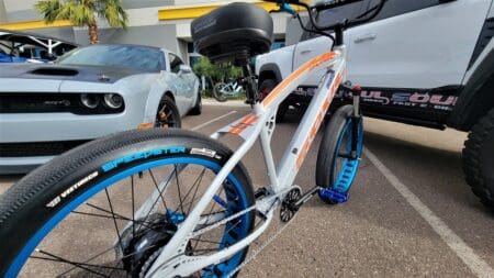 White bicycle parked between two cars.