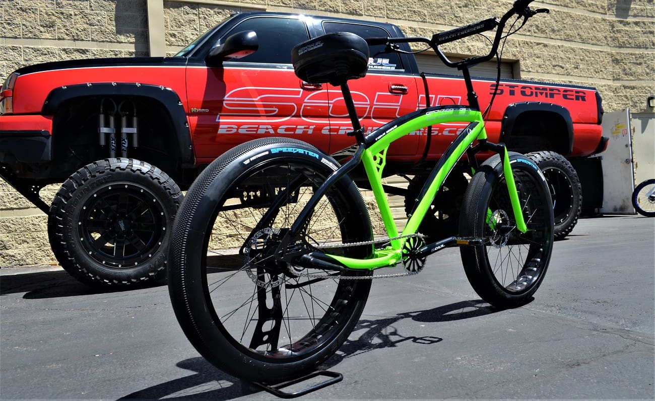 Green bicycle in front of red truck.