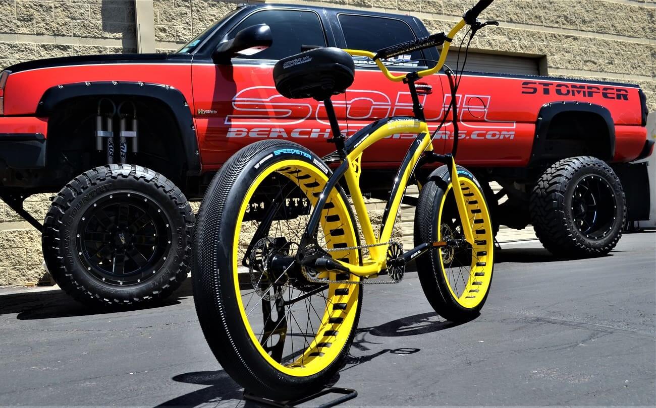 Yellow bike and red truck on pavement.