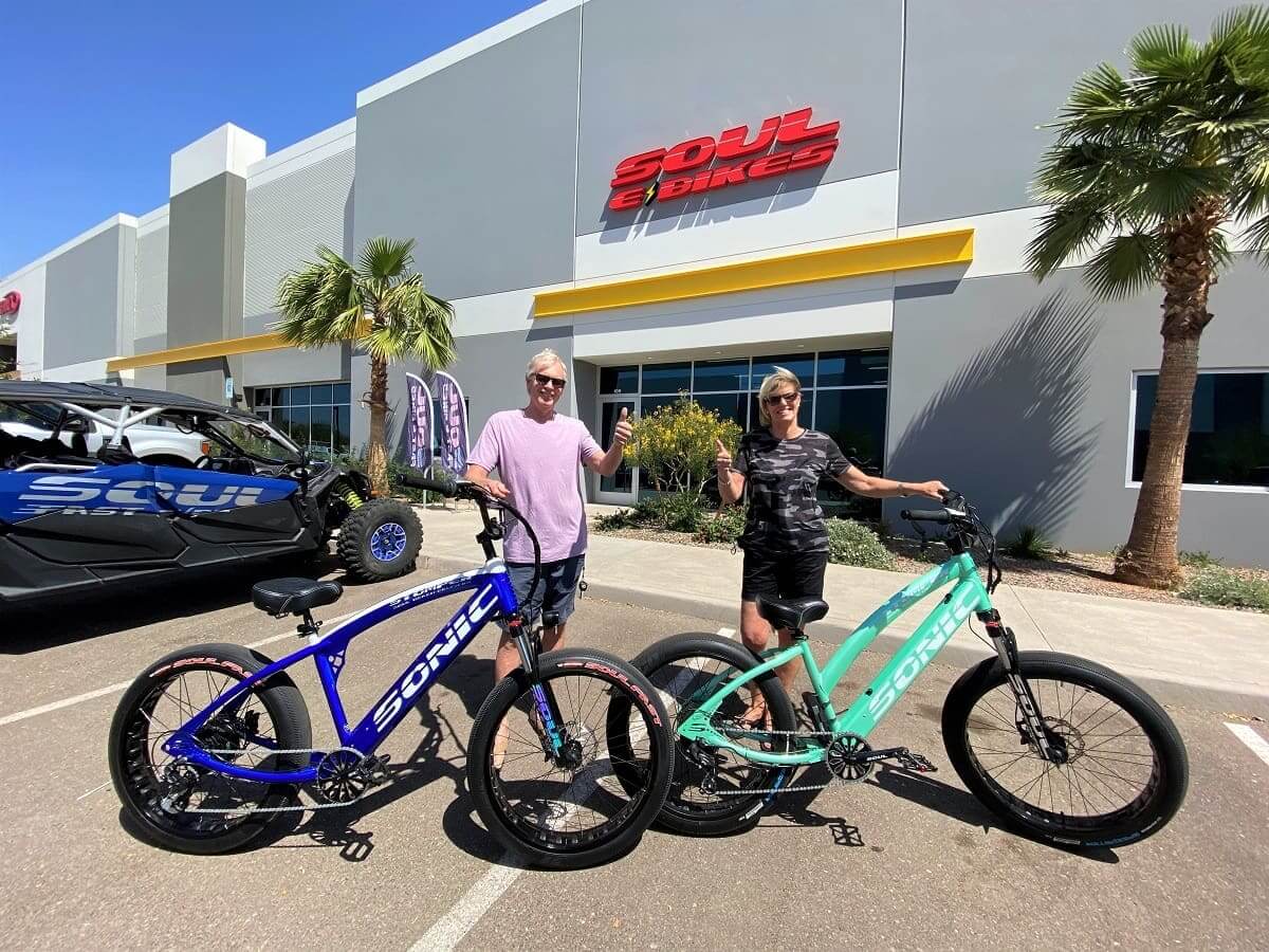 Two people holding Soul Bikes outside store.