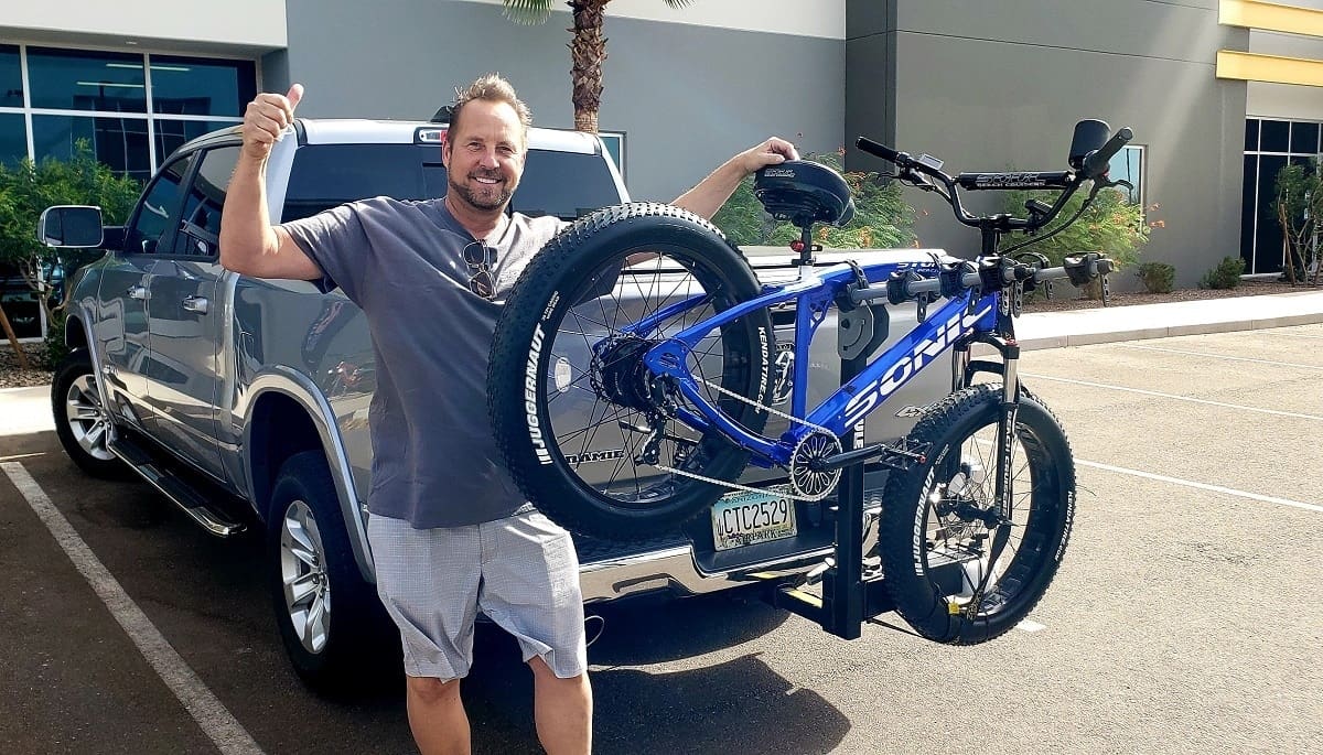 Man posing with bike on truck rack.