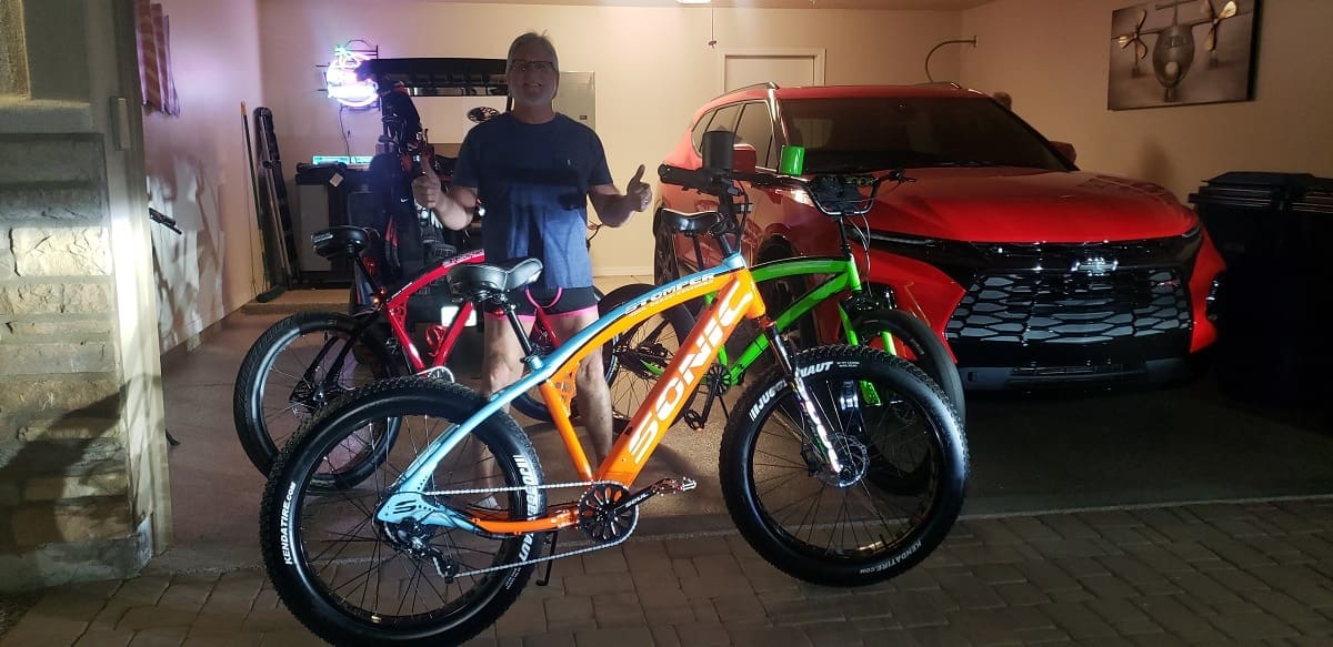 Man standing with bikes in garage.