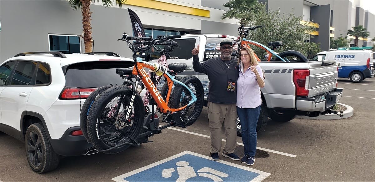 Two people with bikes in parking lot.
