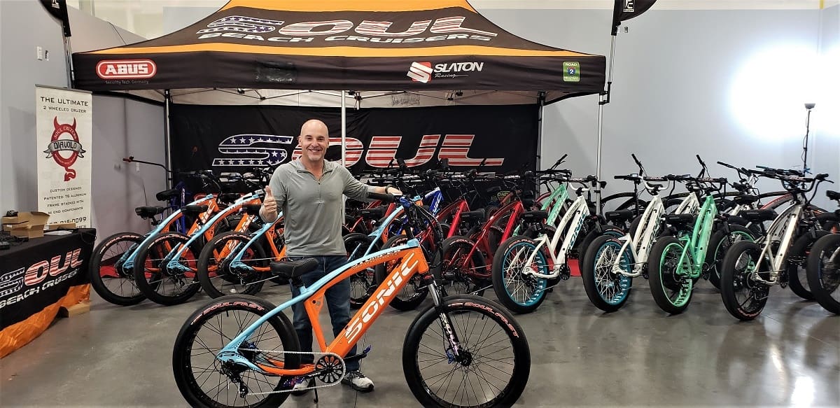 Man standing with bicycle in showroom.