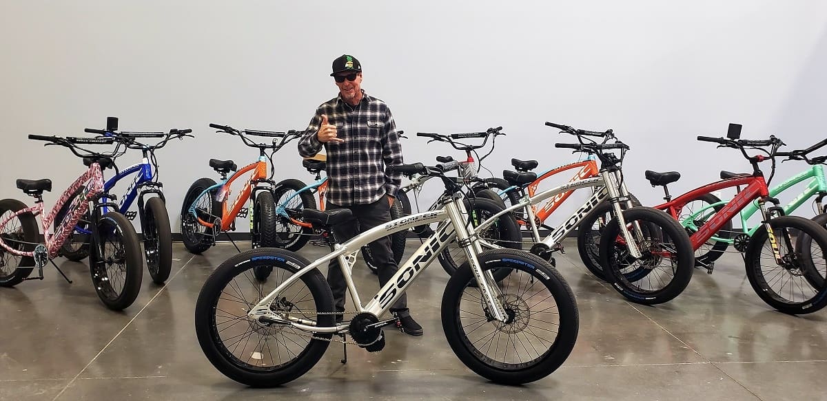 Man with thumbs up in bicycle showroom.