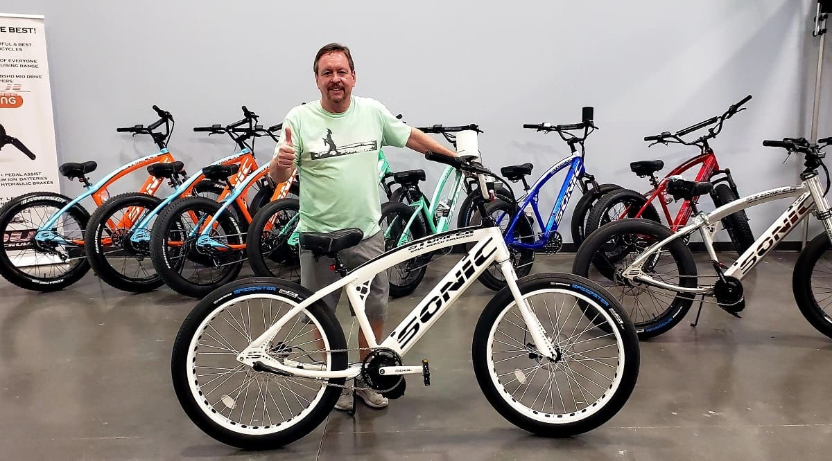 Man with bikes, giving thumbs up gesture.