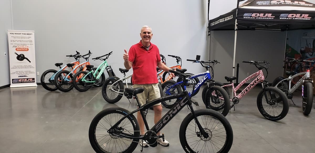 Man standing with various colorful bicycles displayed.