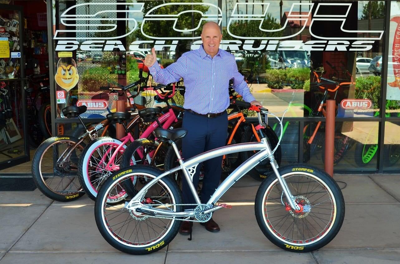Man standing with bicycles outside shop.