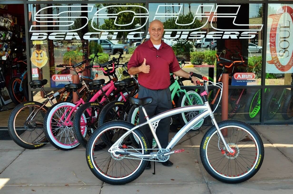 Man standing with bicycles in front of shop.