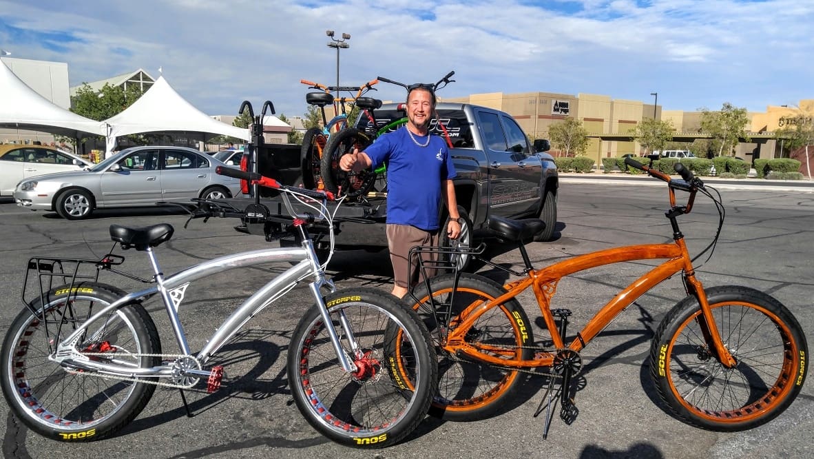 Man standing with two bicycles in parking.
