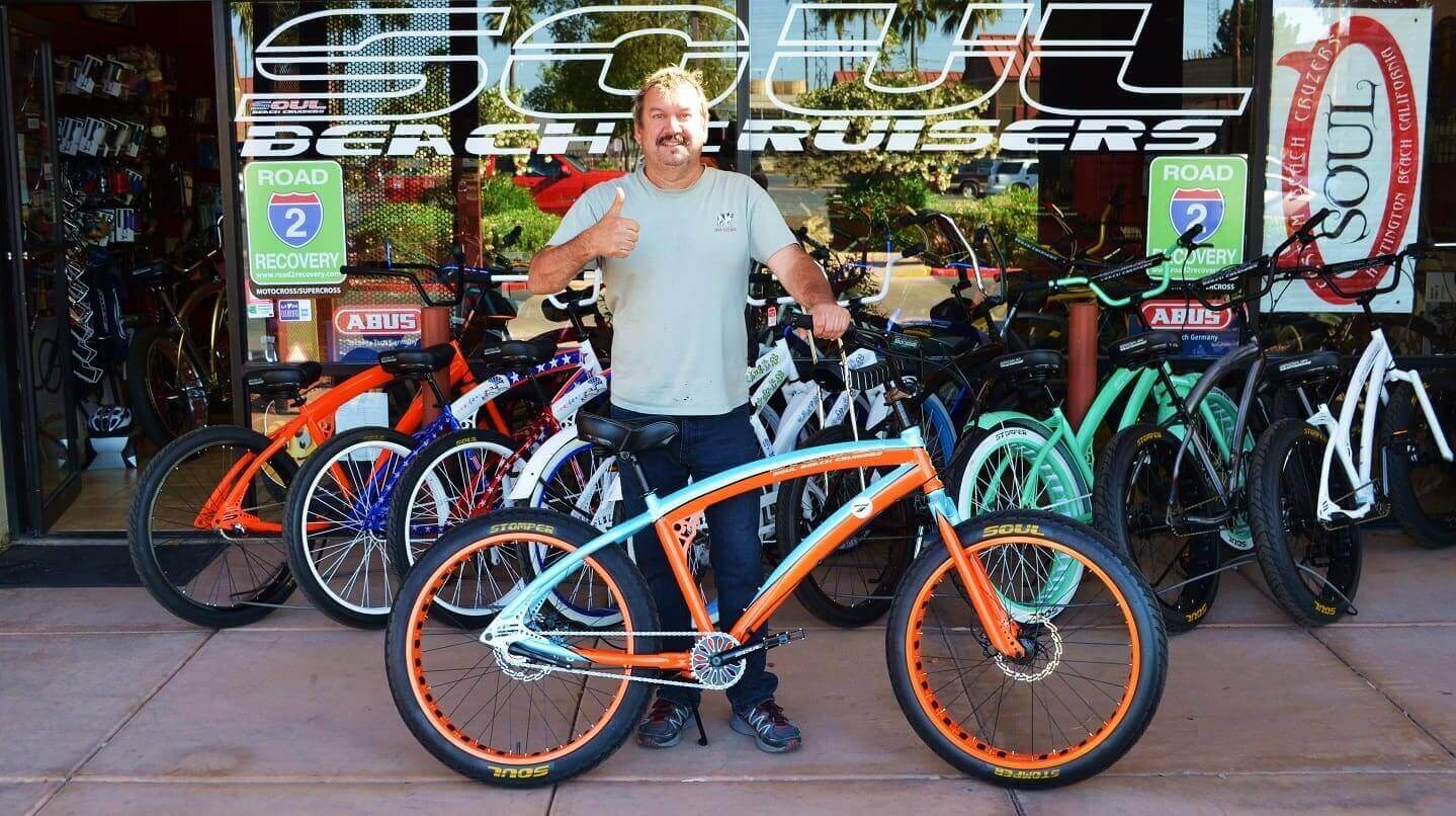 Man standing with colorful beach cruiser bikes.
