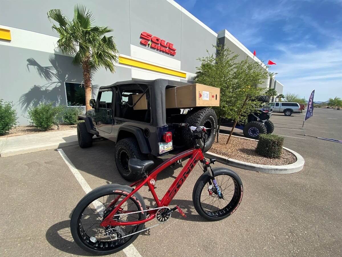 Red bicycle and jeep outside a store.