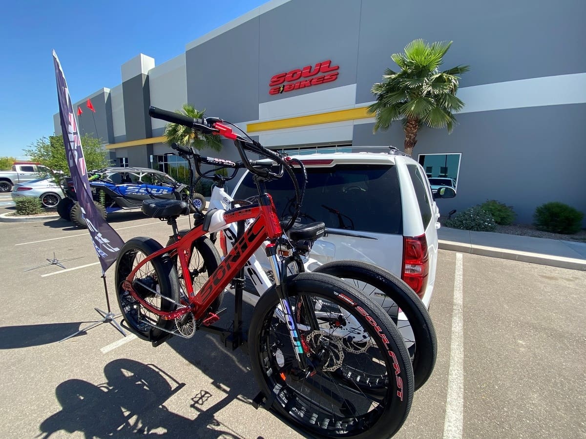 Bicycles mounted on car in parking lot.