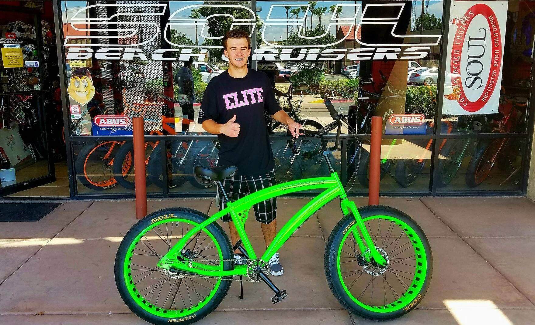 Man with green bike outside store.