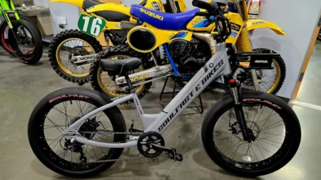 Electric bike displayed alongside vintage motorcycles.