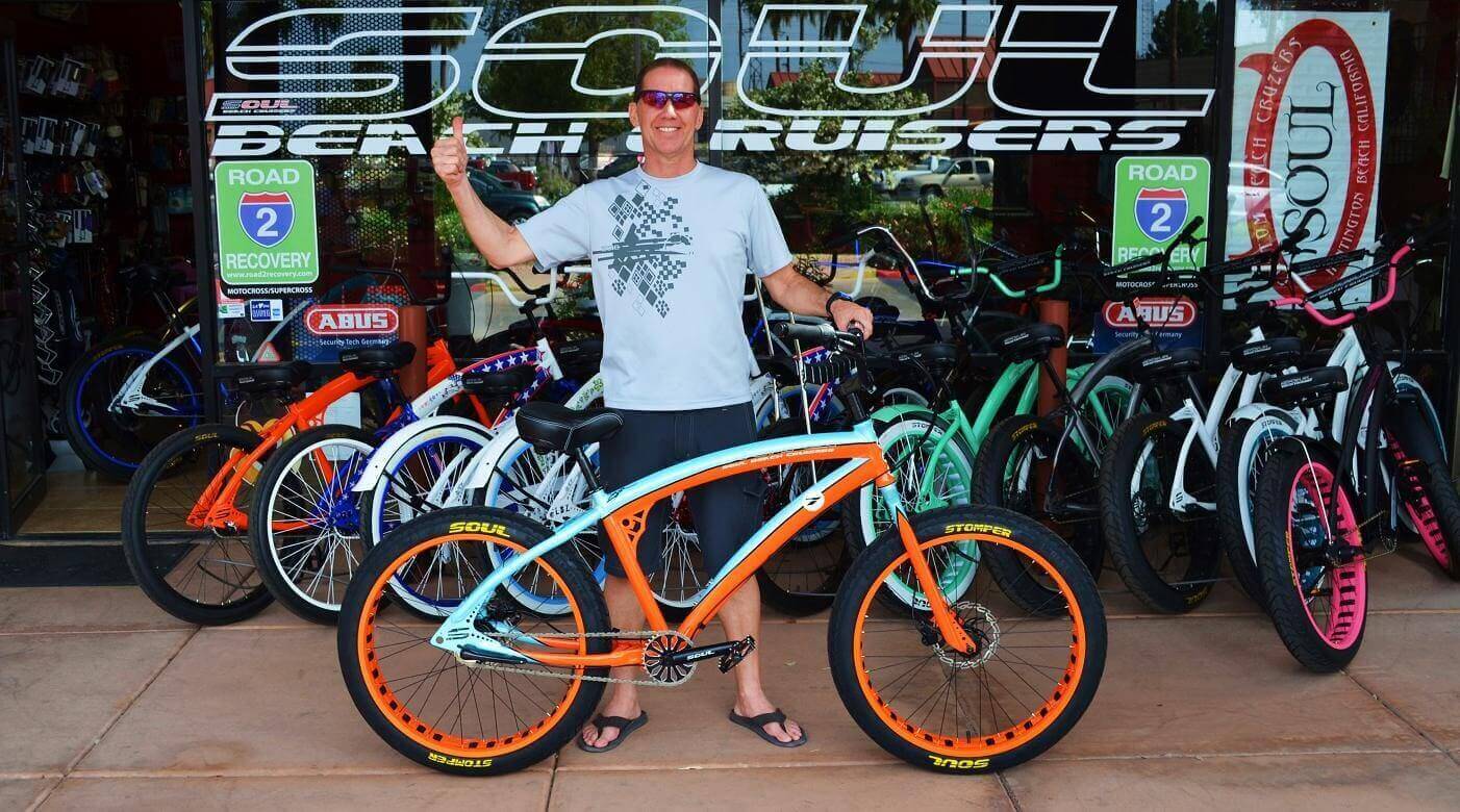 Man posing with colorful beach cruiser bike.