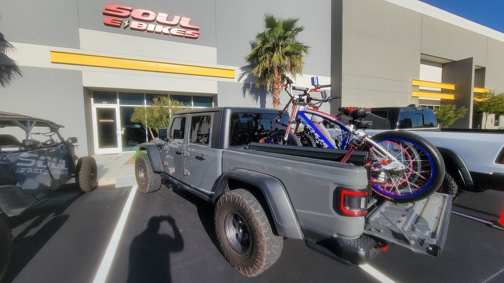 Truck carrying bicycles parked outside e-bike shop.
