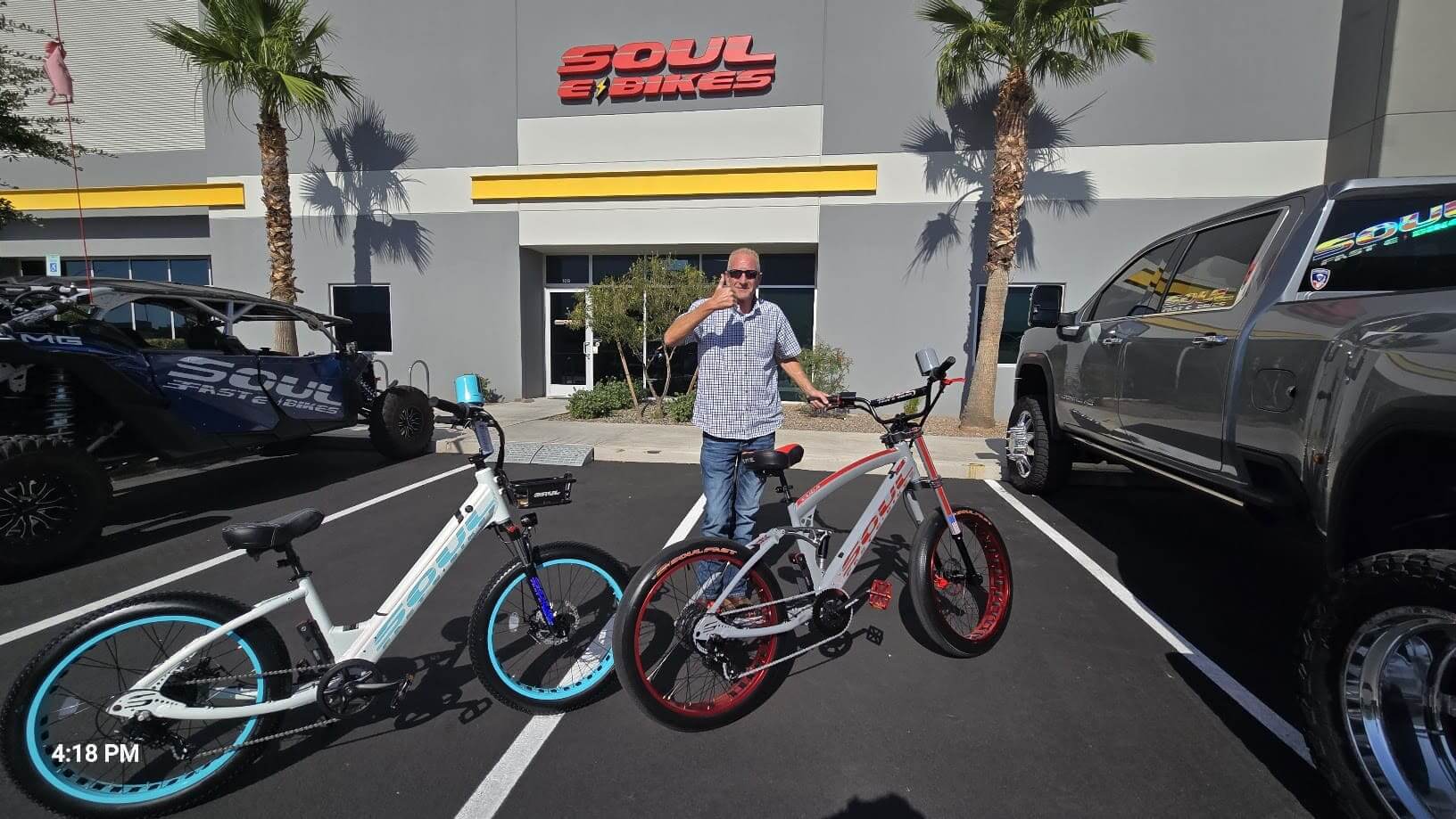 Man standing with two bicycles outside shop.