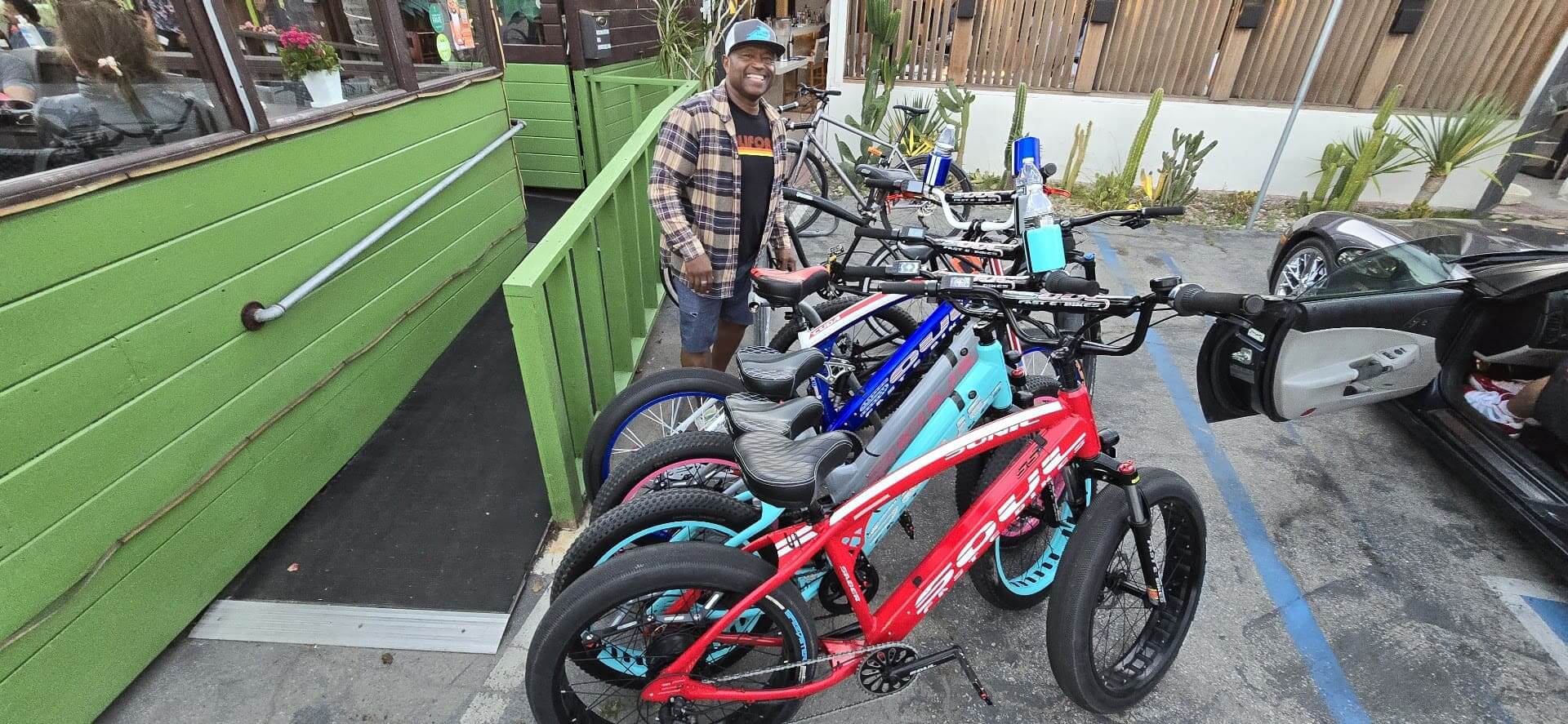 Man standing next to colorful parked bicycles.