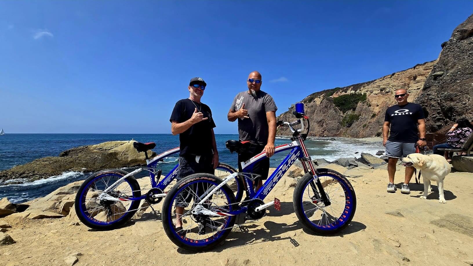 Cyclists posing by the ocean with bikes.